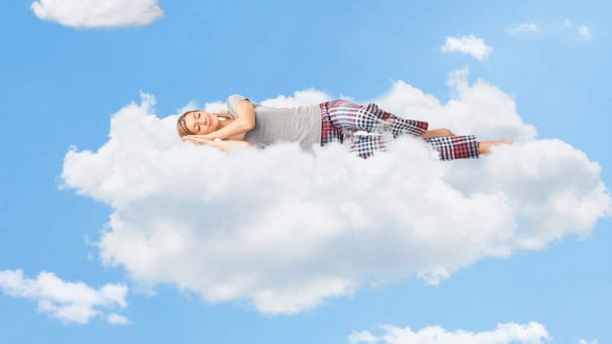 Woman dreaming and sleeping on a cloud up in the sky.