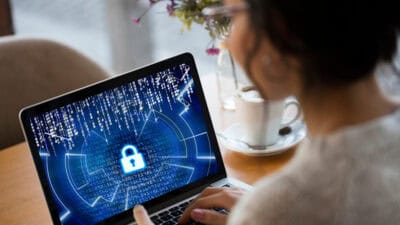 Woman on laptop with screen showing lock with numbers in the background.