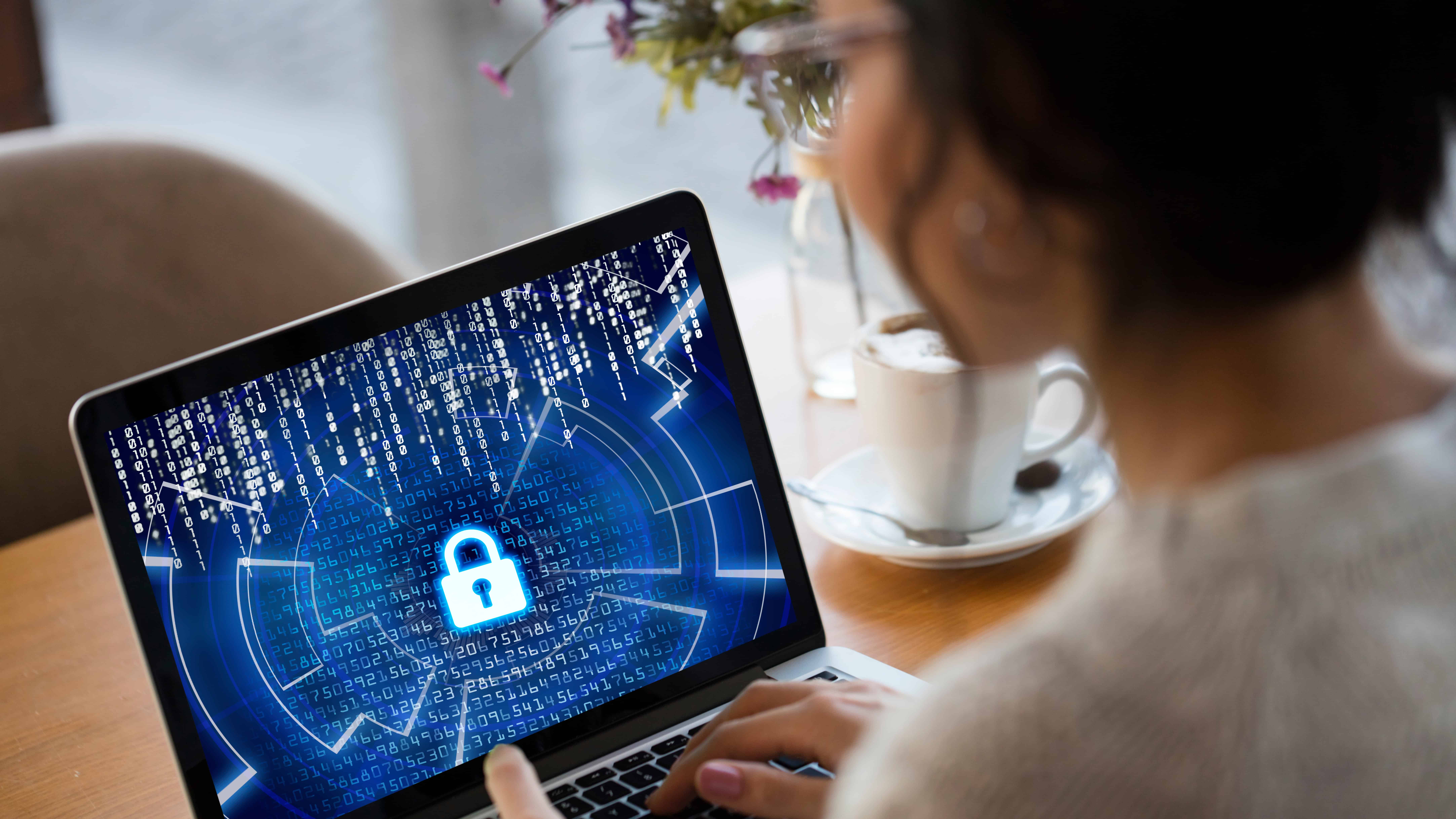 Woman on laptop with screen showing lock with numbers in the background.