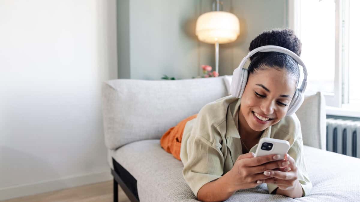 Smiling woman listening to music and using her phone.