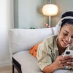 Smiling woman listening to music and using her phone.
