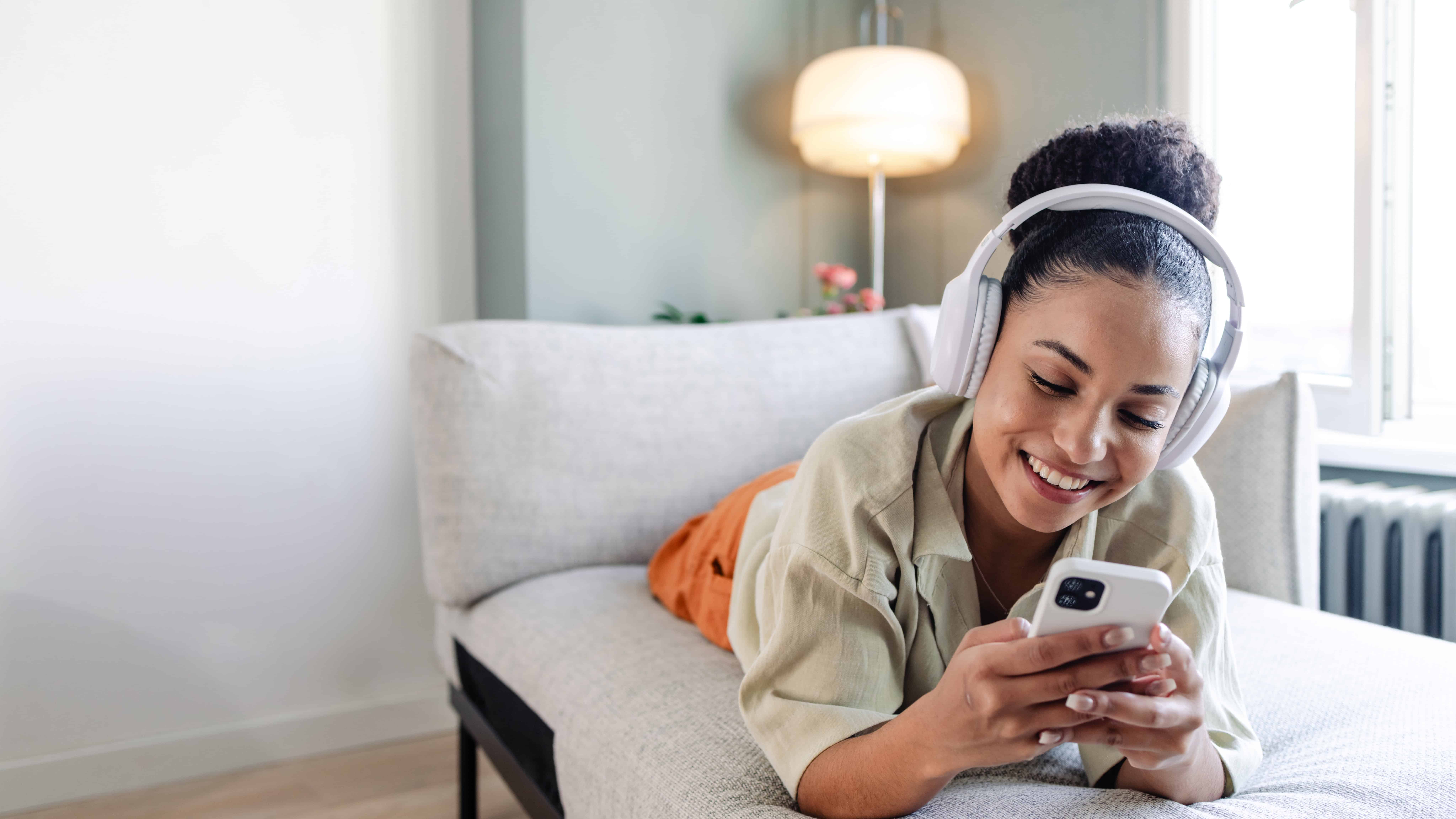 Smiling woman listening to music and using her phone.