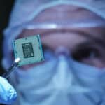 Engineer in sterile coverall holds microchip.