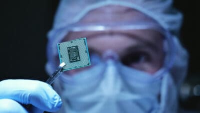 Engineer in sterile coverall holds microchip.