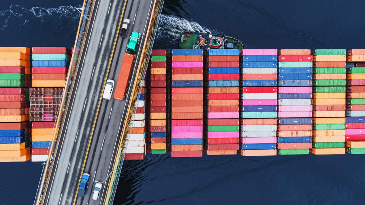 A container ship passes beneath a suspension bridge.