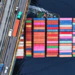 A container ship passes beneath a suspension bridge.