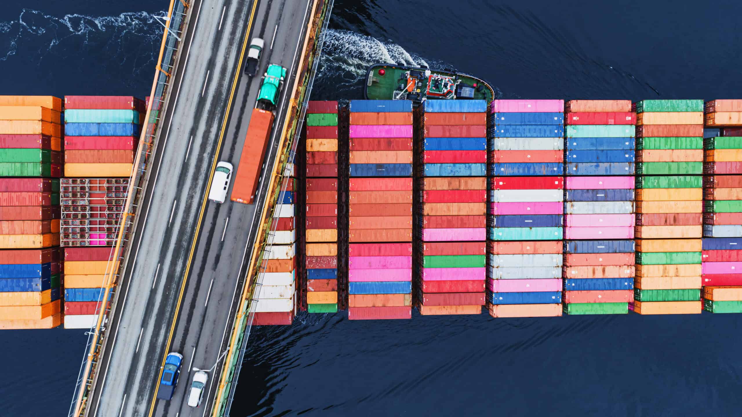 A container ship passes beneath a suspension bridge.