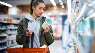 Woman buying diary product and reading food label in grocery store.