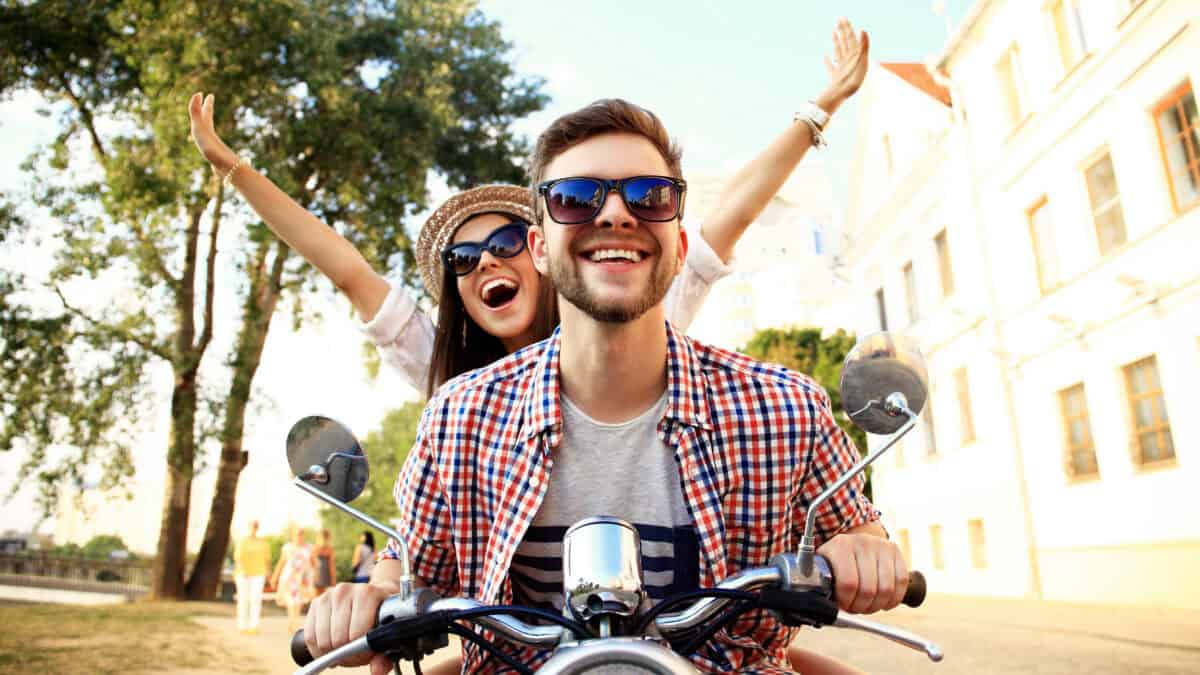 Happy young couple riding a motorbike together.