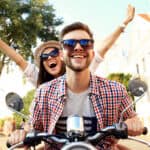 Happy young couple riding a motorbike together.