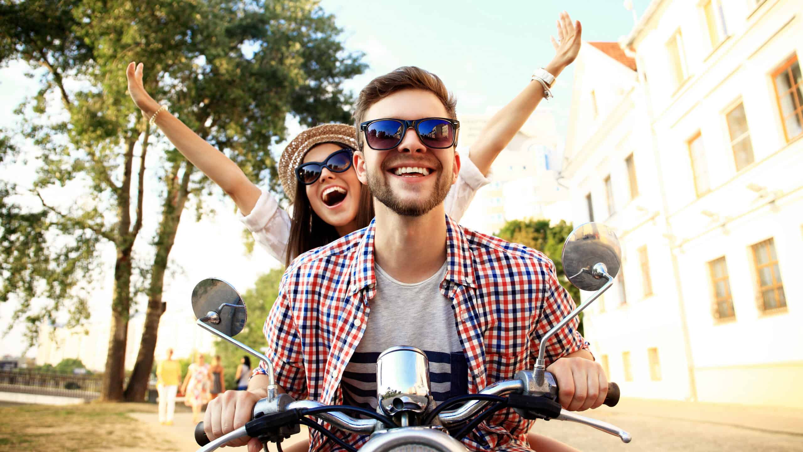 Happy young couple riding a motorbike together.