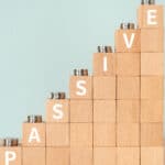 Passive written in white on an increasing pile of wooden blocks with coins on them.