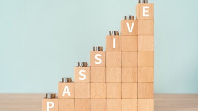 Passive written in white on an increasing pile of wooden blocks with coins on them.