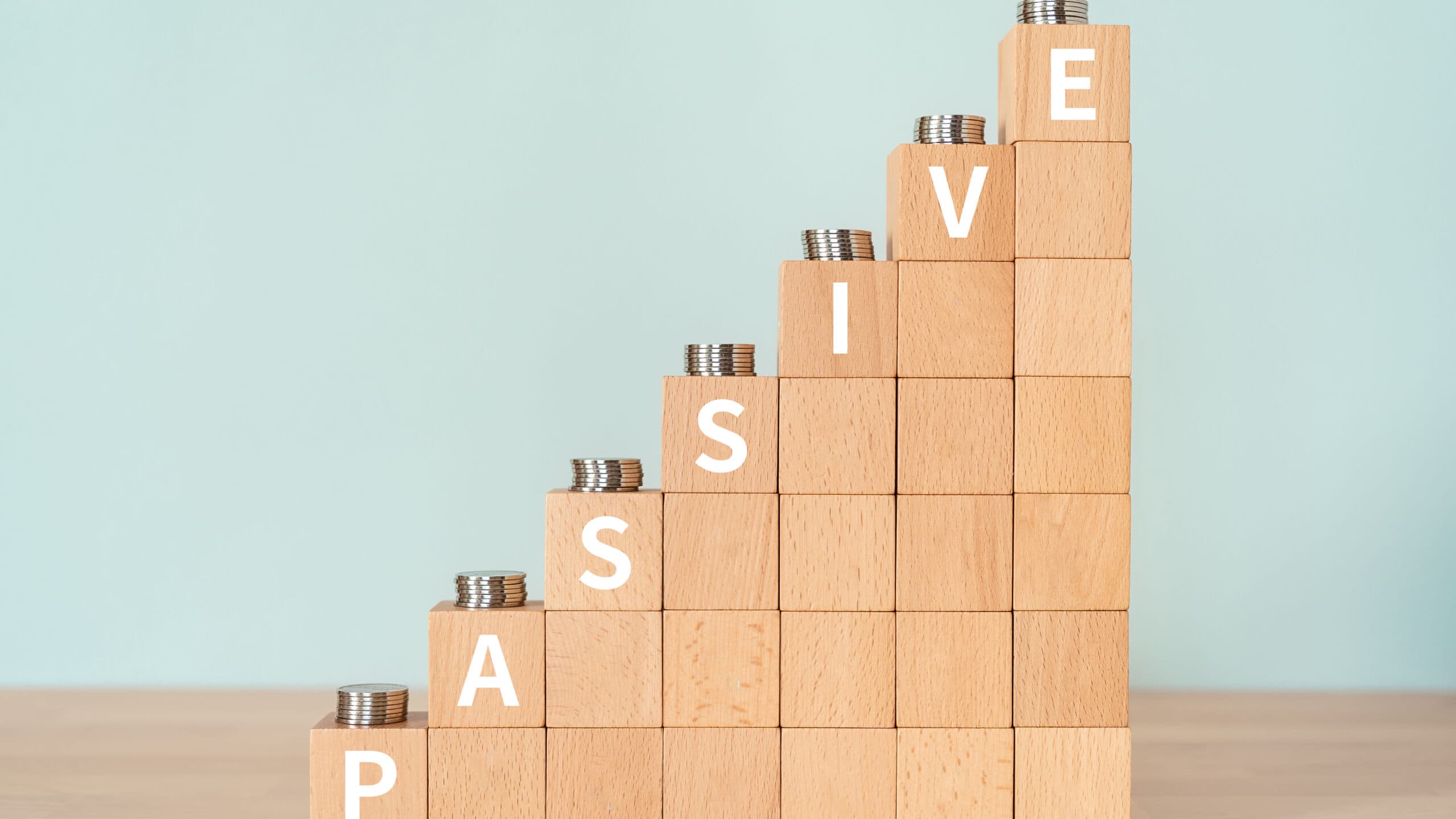 Passive written in white on an increasing pile of wooden blocks with coins on them.