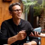 Smiling man paying for his order from his phone on an EFTPOS machine at a restaurant.