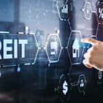 Hand pressing on digital screen with REIT related images.