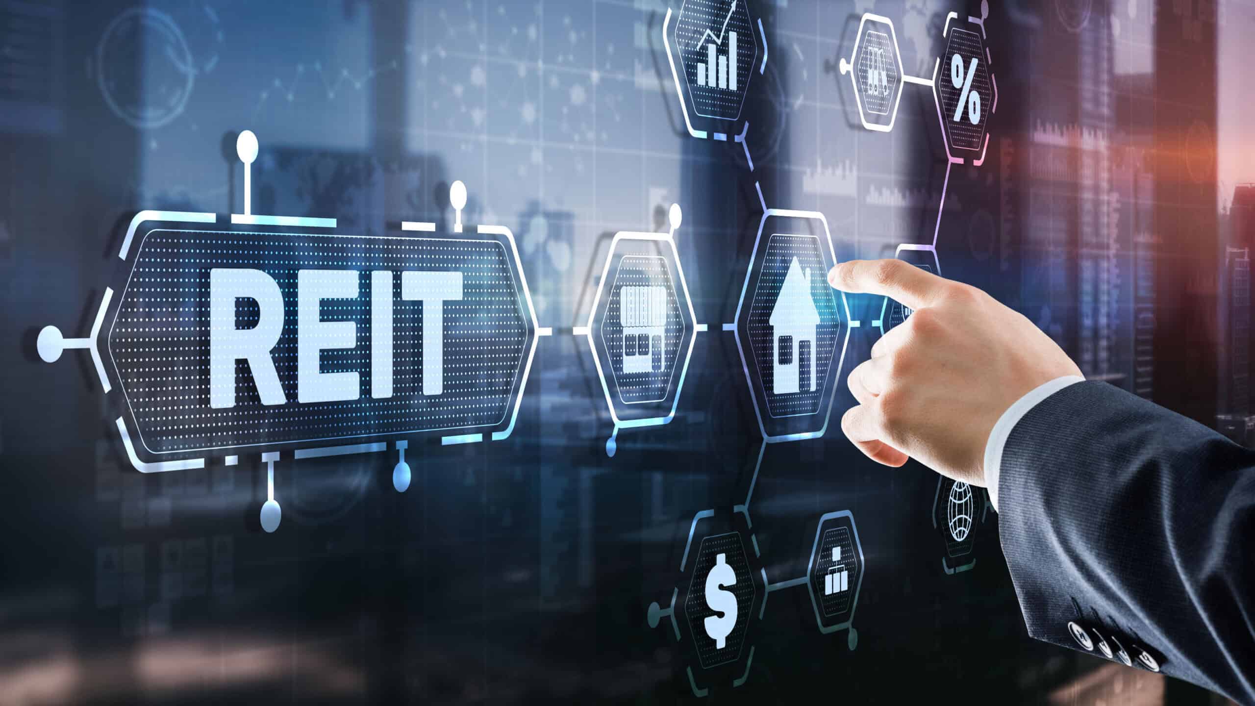 Hand pressing on digital screen with REIT related images.