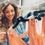 Smiling woman checking out clothes at a shop.