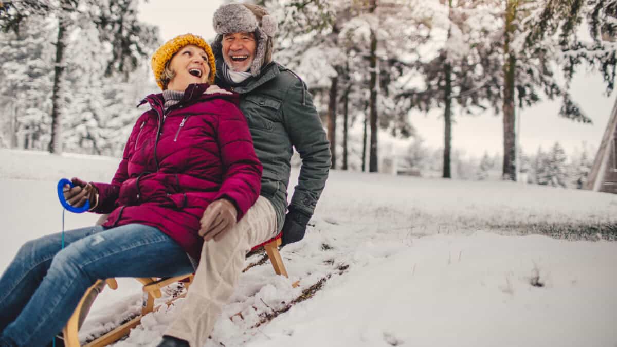 Senior couple sledding in the snow.