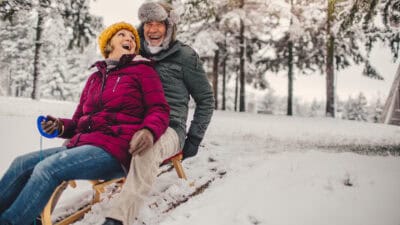 Senior couple sledding in the snow.