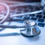 Stethoscope and a pen on a laptop.