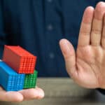 Model shipping containers in one hand, with the other hand doing a halt gesture.