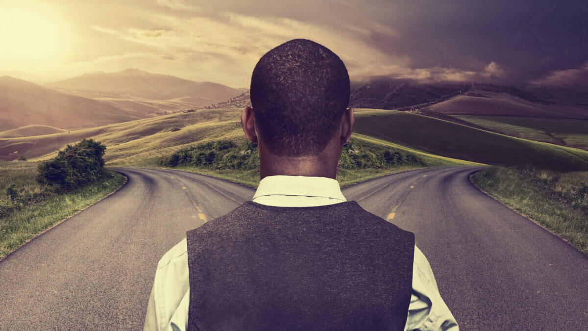 Man looking at two roads going in different directions.