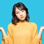 Woman with her hands out to each side on a light blue background.