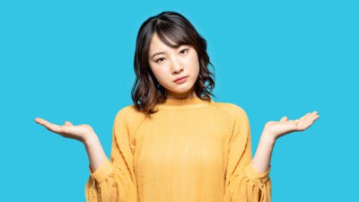 Woman with her hands out to each side on a light blue background.