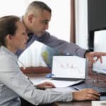 Two colleagues looking at a graph and comparing share prices.