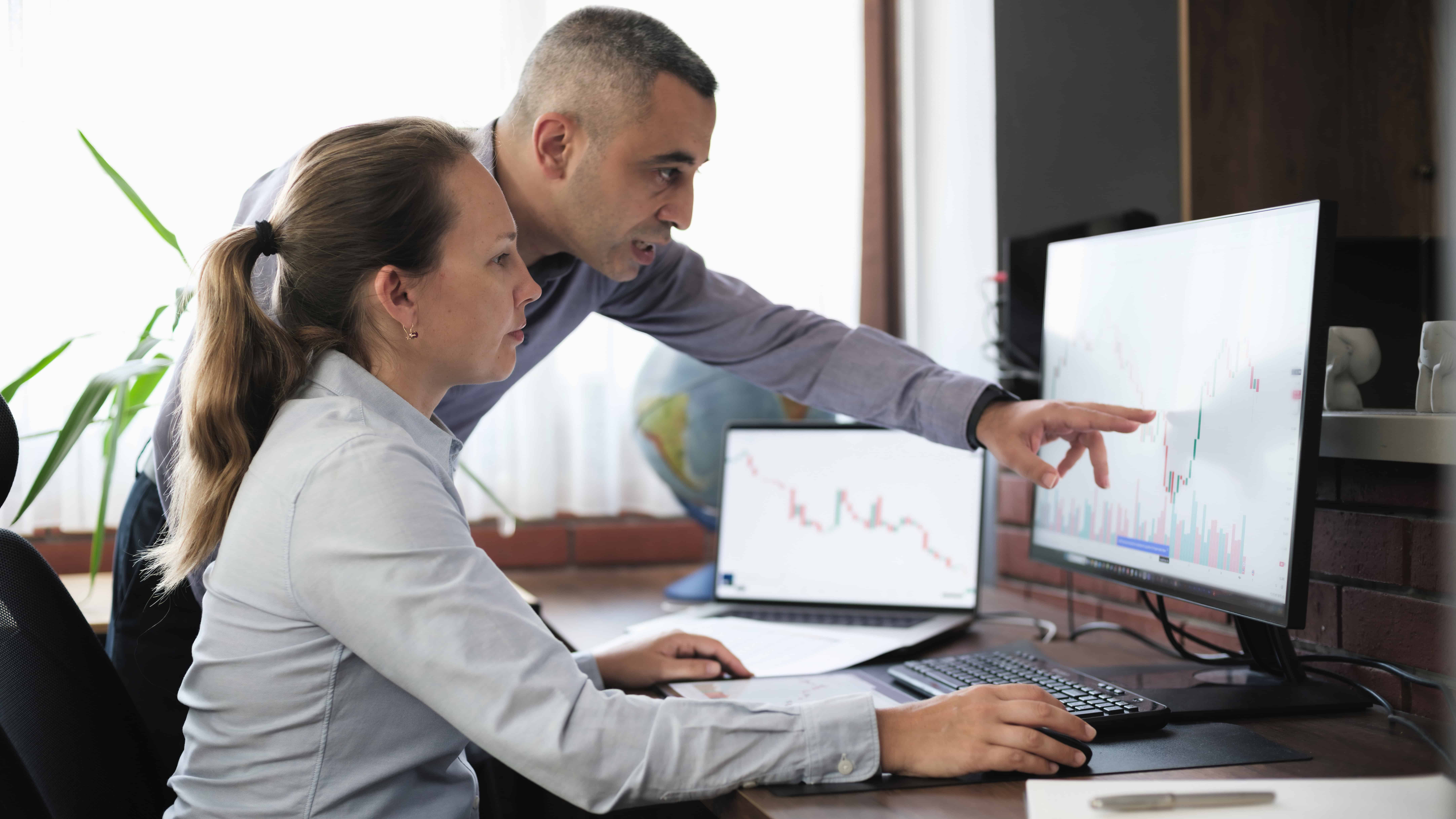 Two colleagues looking at a graph and comparing share prices.