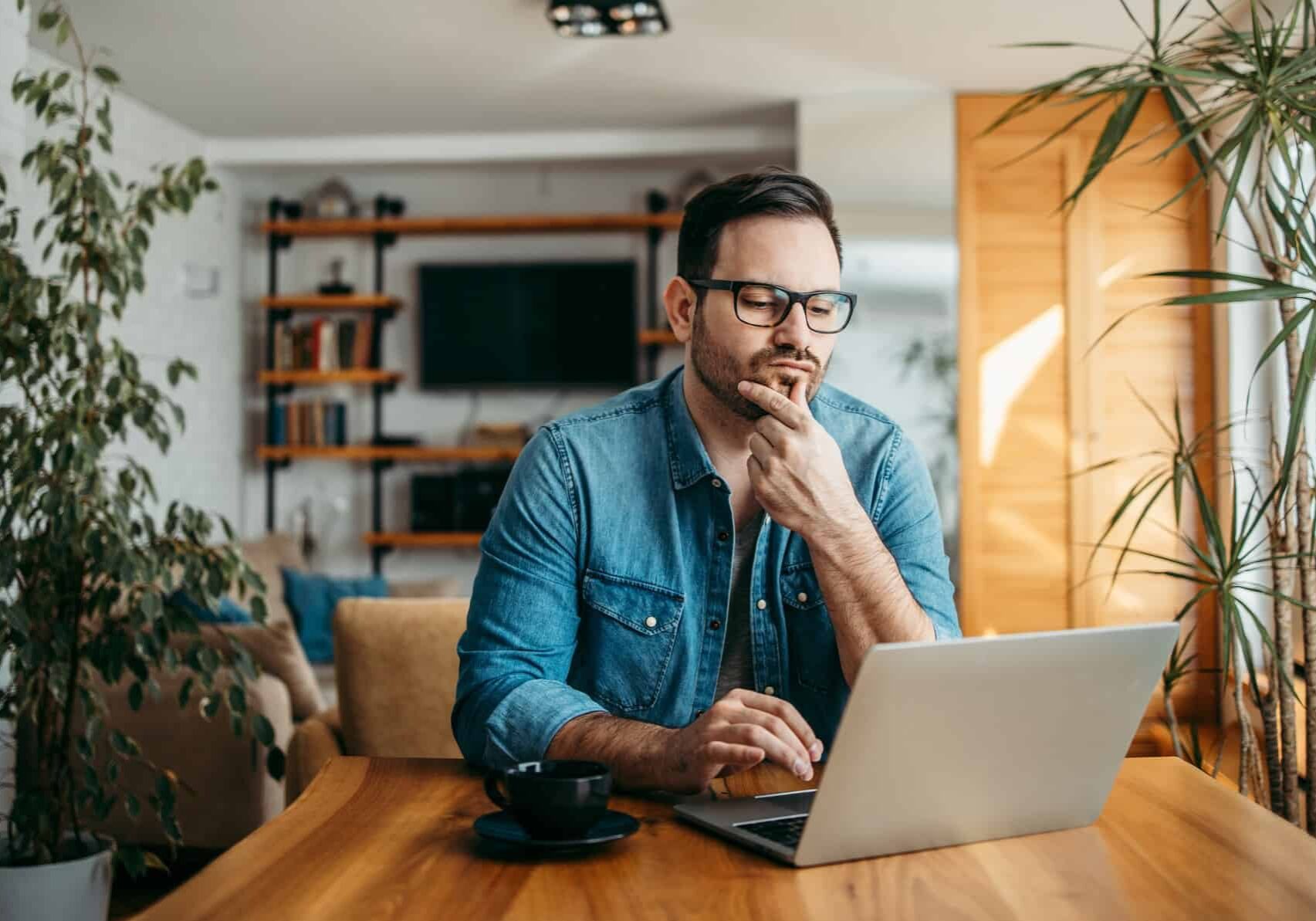 A man sitting at his dining table looks at his laptop and ponders the CSL balance sheet and the value of CSL shares today