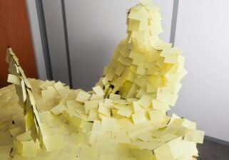 An office worker and his desk covered in yellow post-it notes